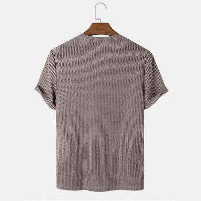 Men's summer round neck solid color T-shirt in beige with short sleeves, hanging on a wooden hanger.