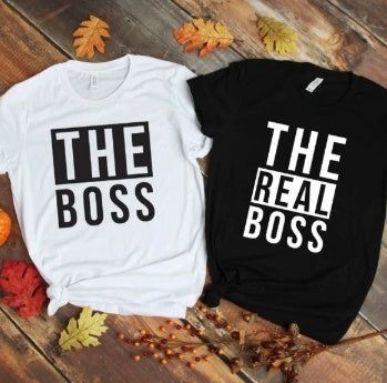 Two DIY men's T-shirts with bold letter prints reading "THE BOSS" in white and "THE REAL BOSS" in black, styled on a wooden background with autumn leaves.